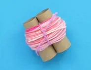 Meer lagen roze wol worden om de rollen gewikkeld en vormen een lus van 3 cm die op zijn plaats is vastgemaakt met een touwtje van roze wol.
