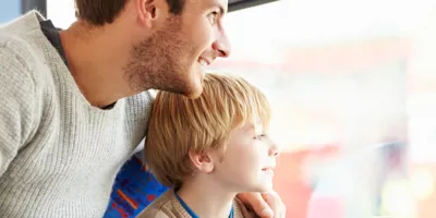 Een man en een jongen kijken uit het raam van een bus en wijzen naar bezienswaardigheden.
