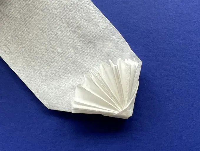 Waaier gevouwen in het uiteinde van een strook wc-papier op een blauwe achtergrond.