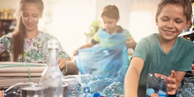 Kinderen sorteren thuis plastic flessen voor recycling.