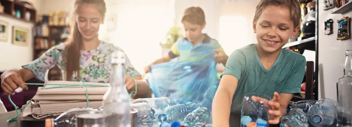 Kinderen sorteren thuis plastic flessen voor recycling.