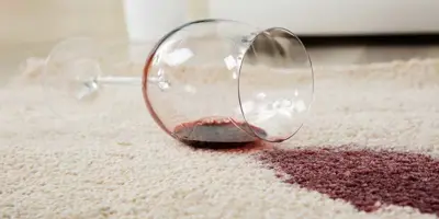 Wijnglas omgevallen op een crème tapijt vormt een wijnvlek