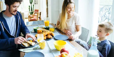 Een gezin van drie zit 's ochtends aan tafel te ontbijten