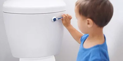 Een kleine jongen spoelt het toilet door