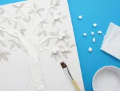 Propjes wc-papier worden geplakt op een tekening van een boom gevuld met repen keukenpapier met kartonnen blaadjes.