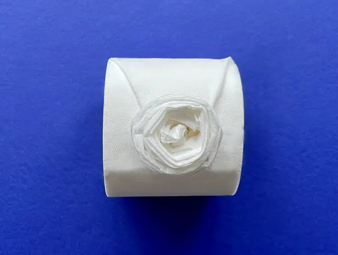 Wc-papier in origamiroos gevouwen op een wc-rol op een blauwe achtergrond.
