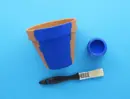 Deels blauw geverfde terracotta bloempot met verfpotje en kwast ernaast.