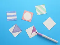 Zes kartonnen vierkantjes: vier met gekleurde patronen en de vijfde deels ingekleurd met de paarse stift die erbij ligt.