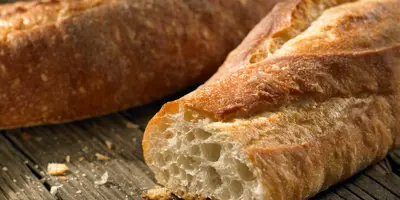 Close-up van een doorgesneden knapperig wit stokbrood met kruimels en een tweede stokbrood in de achtergrond