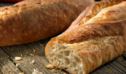 Close-up van een doorgesneden knapperig wit stokbrood met kruimels en een tweede stokbrood in de achtergrond 