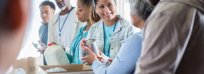 Een vrouw overhandigt een andere vrouw een onopvallend blikje eten.