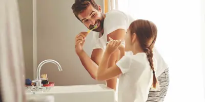 Een man en zijn jonge dochter leren hoe je water kunt besparen, terwijl ze samen tandenpoetsen in een badkamer