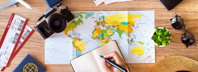 Een tafel met paspoorten, kaarten, zonnebrillen, notitieboekje, vliegtickets en een planner