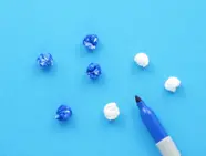 Zeven propjes wc-papier waarvan vier blauw zijn gekleurd met de blauwe stift die erbij ligt.